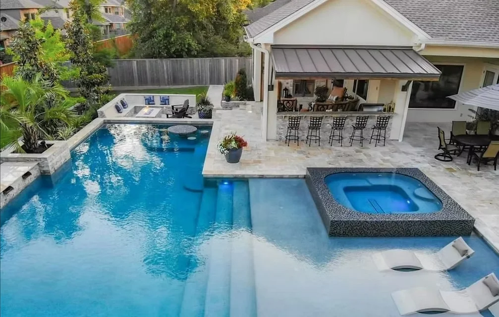 Aerial view of luxury pool with swim-up bar, tanning ledge, and spa in Houston backyard
