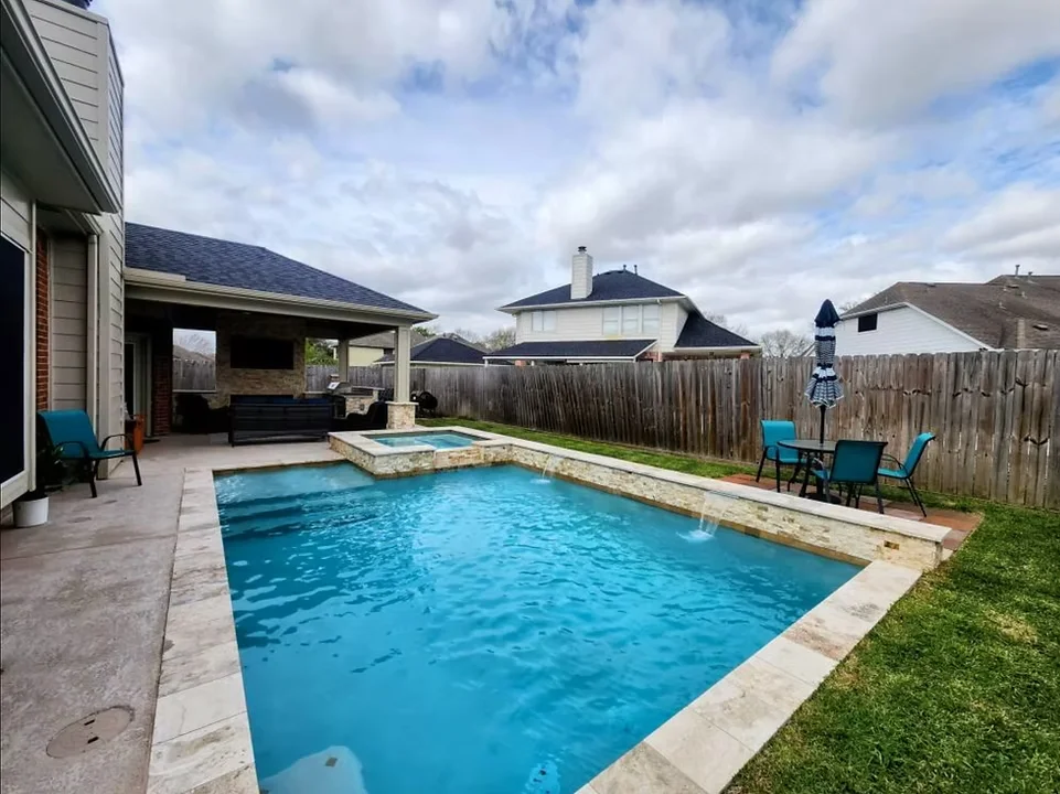 Custom pool with water feature, fire pit, and landscaping in Houston neighborhood