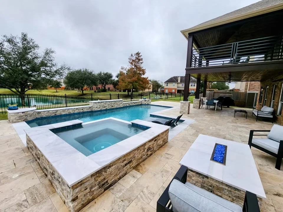 Pool with raised spa, fire table, and covered patio on a lakefront Houston property